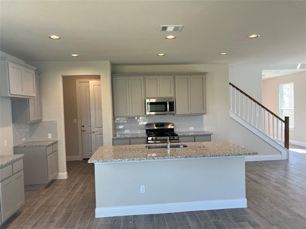 128 Free Stone Drive Georgetown, TX 78628 - Photo 7 of 29 Kitchen featuring a central island with an undermount sink, granite countertops, and light-toned cabinetry
