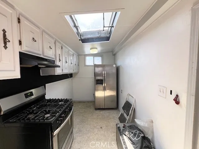 a kitchen with stainless steel appliances granite countertop a refrigerator a sink dishwasher a stove and white cabinets