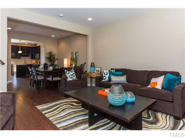707 Wickham Ridge Road, Unit 160 Apex, NC 27539 - Photo 3 of 21 a living room with furniture and a dining table with wooden floor