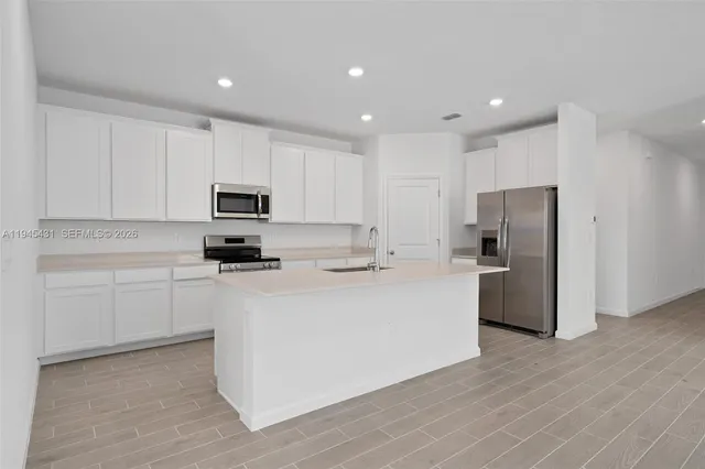 a kitchen with stainless steel appliances granite countertop a refrigerator a stove top oven a sink and dishwasher with wooden floor