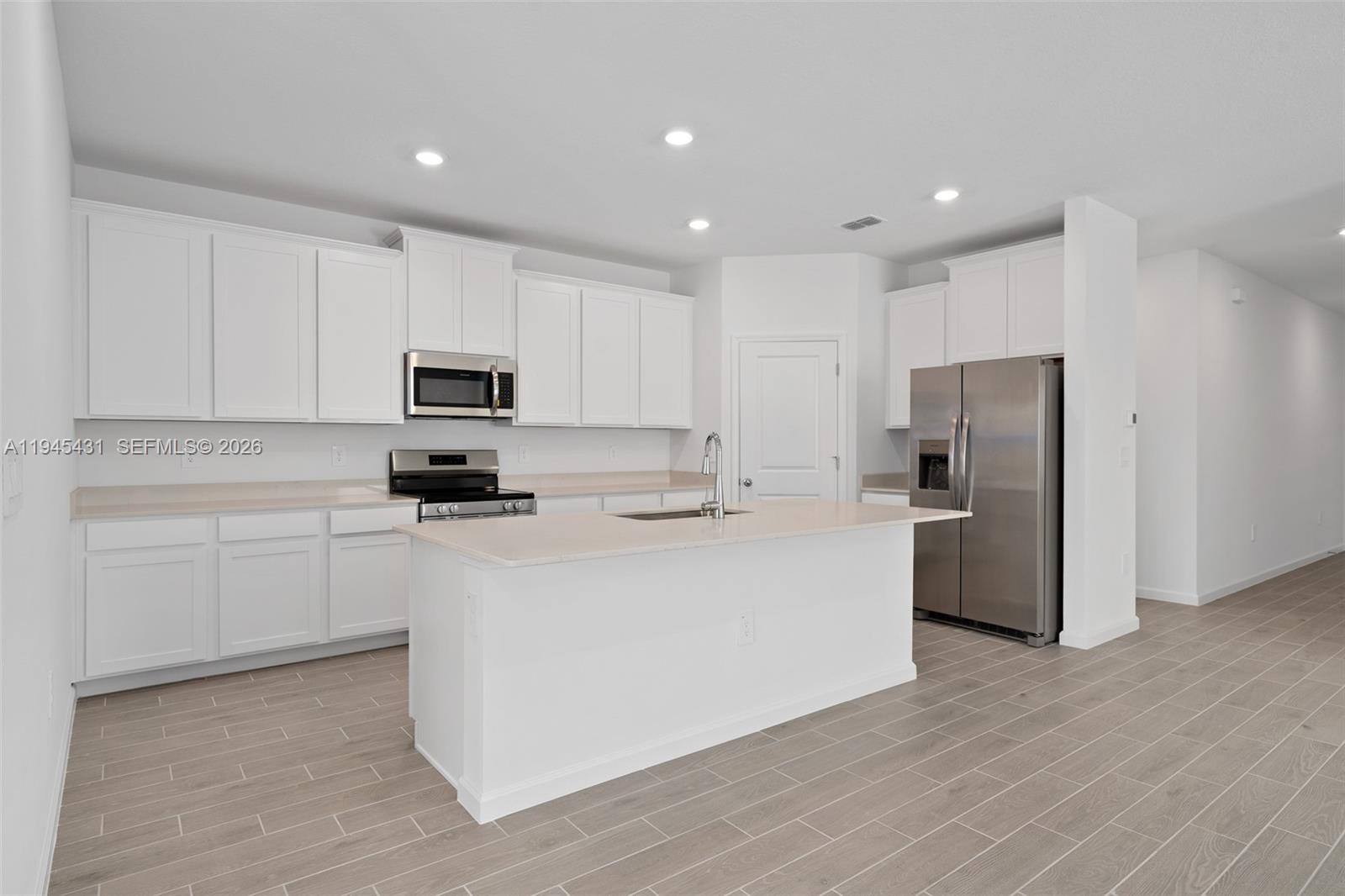 8934 Southwest 69th Terrace Ocala, FL 34476 - Photo 5 of 41 a kitchen with stainless steel appliances granite countertop a refrigerator a stove top oven a sink and dishwasher with wooden floor
