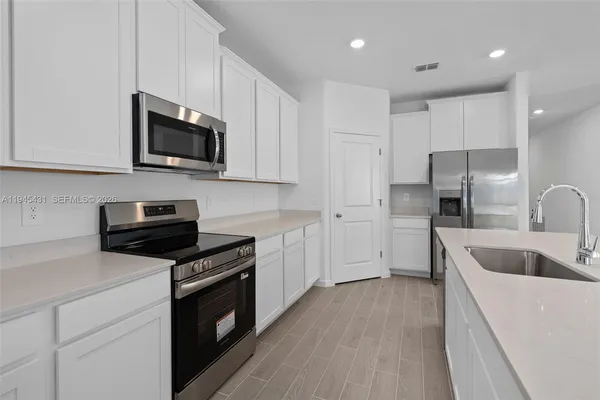 a kitchen with granite countertop a sink a stove a microwave and refrigerator