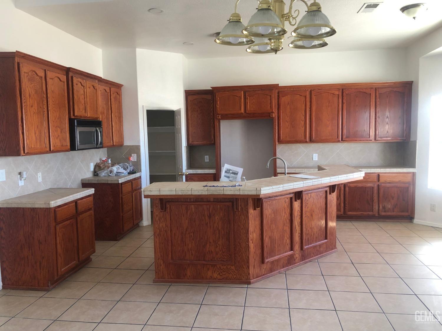 Undisclosed Address Bakersfield, CA 93314 - Photo 18 of 21 a kitchen with kitchen island granite countertop a sink counter top space appliances and cabinets