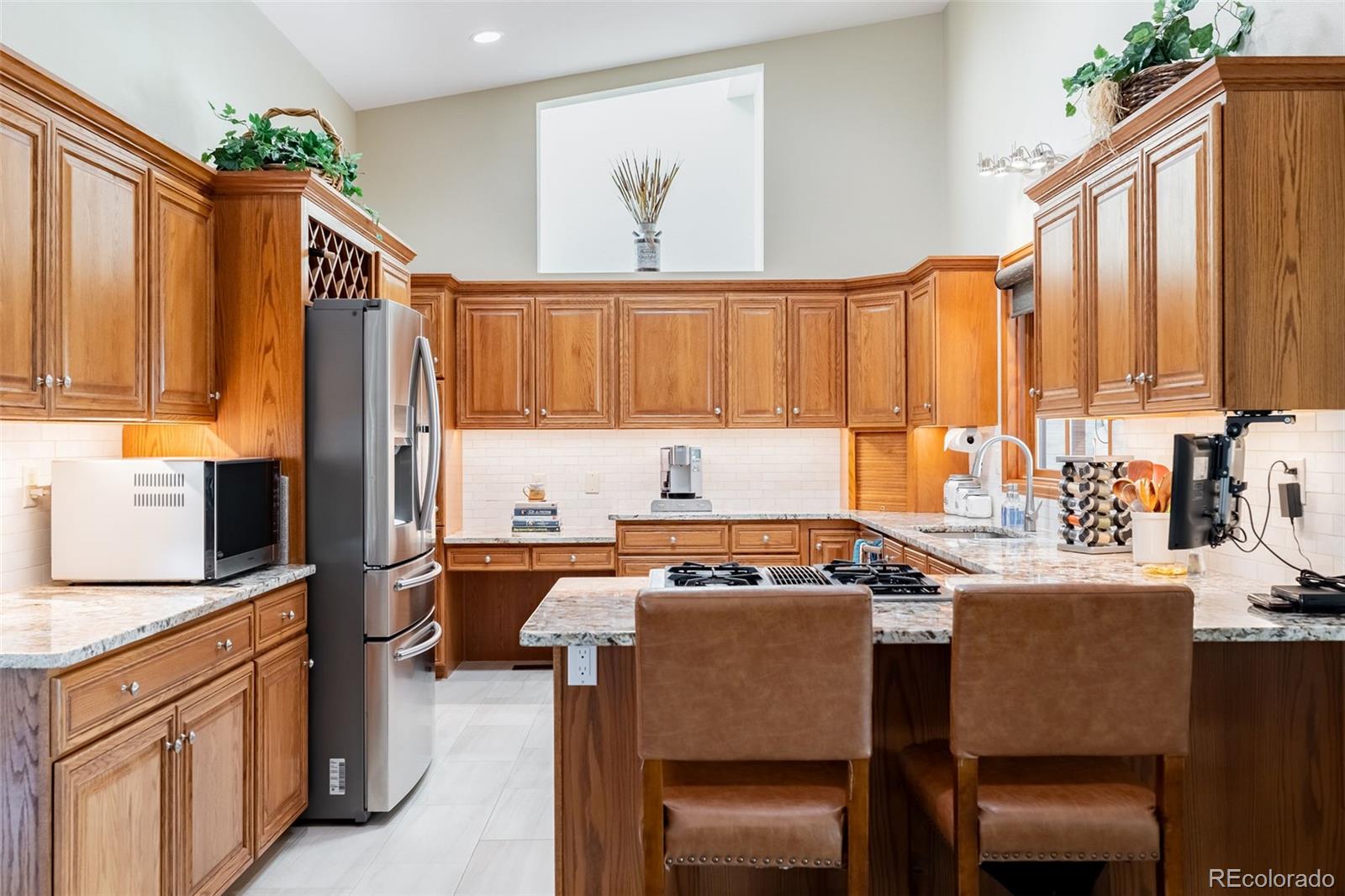 16609 West 77th Drive Arvada, CO 80007 - Photo 9 of 48 a kitchen with stainless steel appliances a stove a sink and a refrigerator