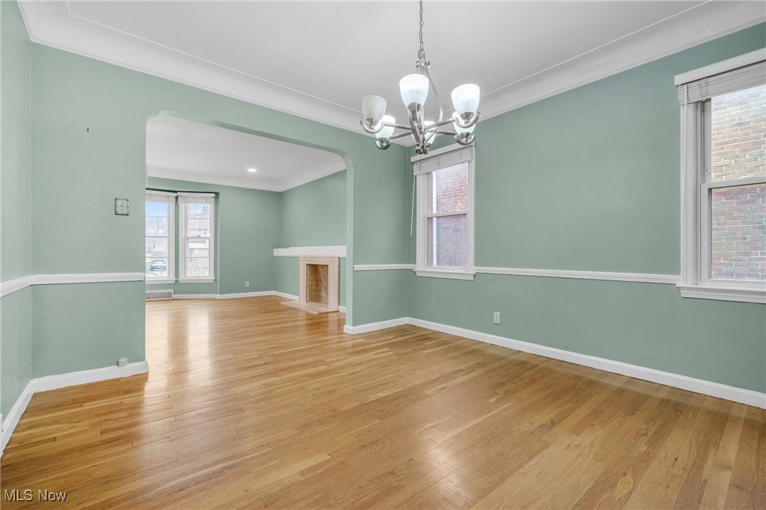 4430 Silsby Road Cleveland, OH 44118 - Photo 17 of 43 Spare room with a notable chandelier, ornamental molding, a wealth of natural light, and light hardwood / wood-style flooring