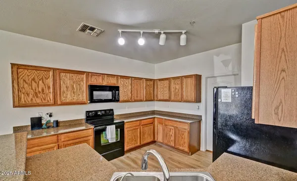 a kitchen with stainless steel appliances granite countertop a stove top oven a sink dishwasher and white cabinets with wooden floor