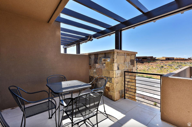 1622 Canyon Tree Drive St. George, UT 84770 - Photo 10 of 34 Outdoor patio featuring an open pergola, stucco walls, stone accent pillar, black metal railing, and concrete flooring