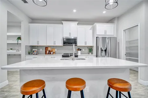 a kitchen with stainless steel appliances granite countertop a sink a stove a refrigerator a counter and chairs