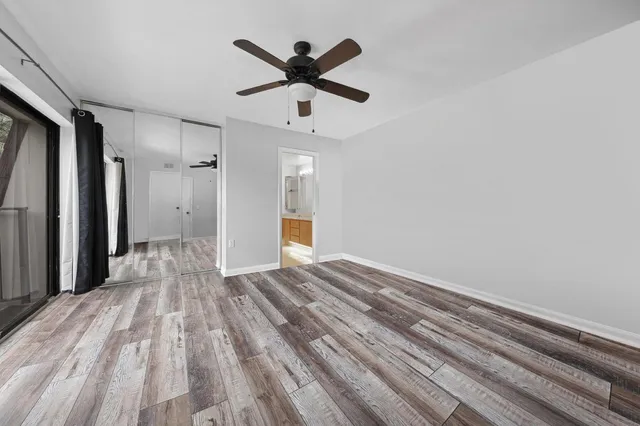 a view of empty room with wooden floor and ceiling fan