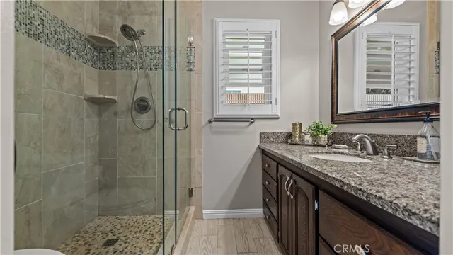 a bathroom with a granite countertop sink a mirror and shower