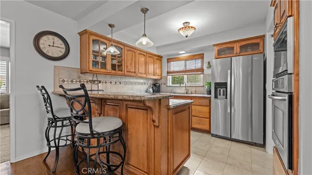 a kitchen with stainless steel appliances granite countertop a stove a refrigerator a kitchen island with chairs and refrigerator