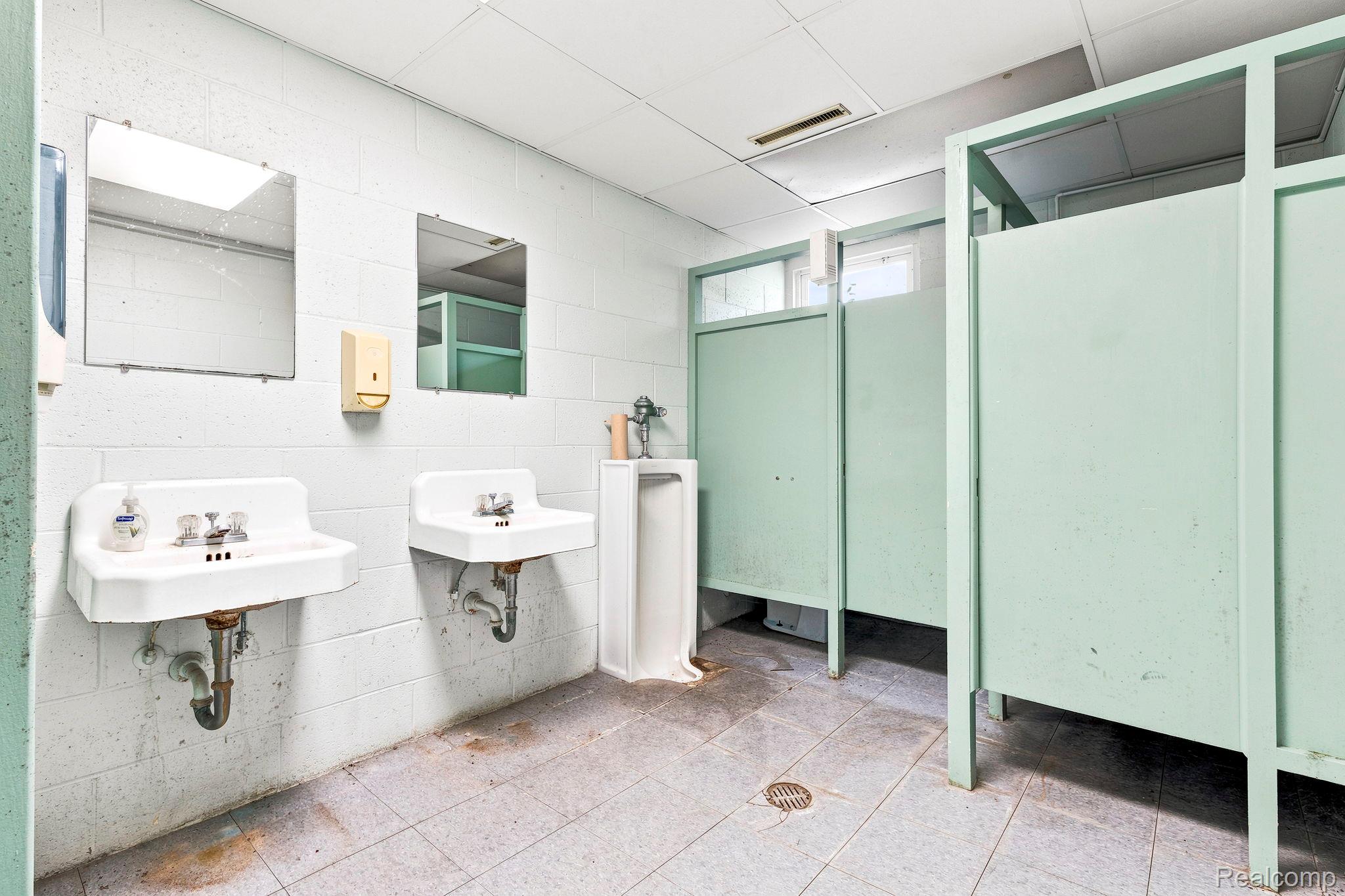 9735 Dolan Road Columbus, MI 48063 - Photo 53 of 63 Restroom featuring multiple wall-mounted sinks, individual stall partitions, and a tiled floor