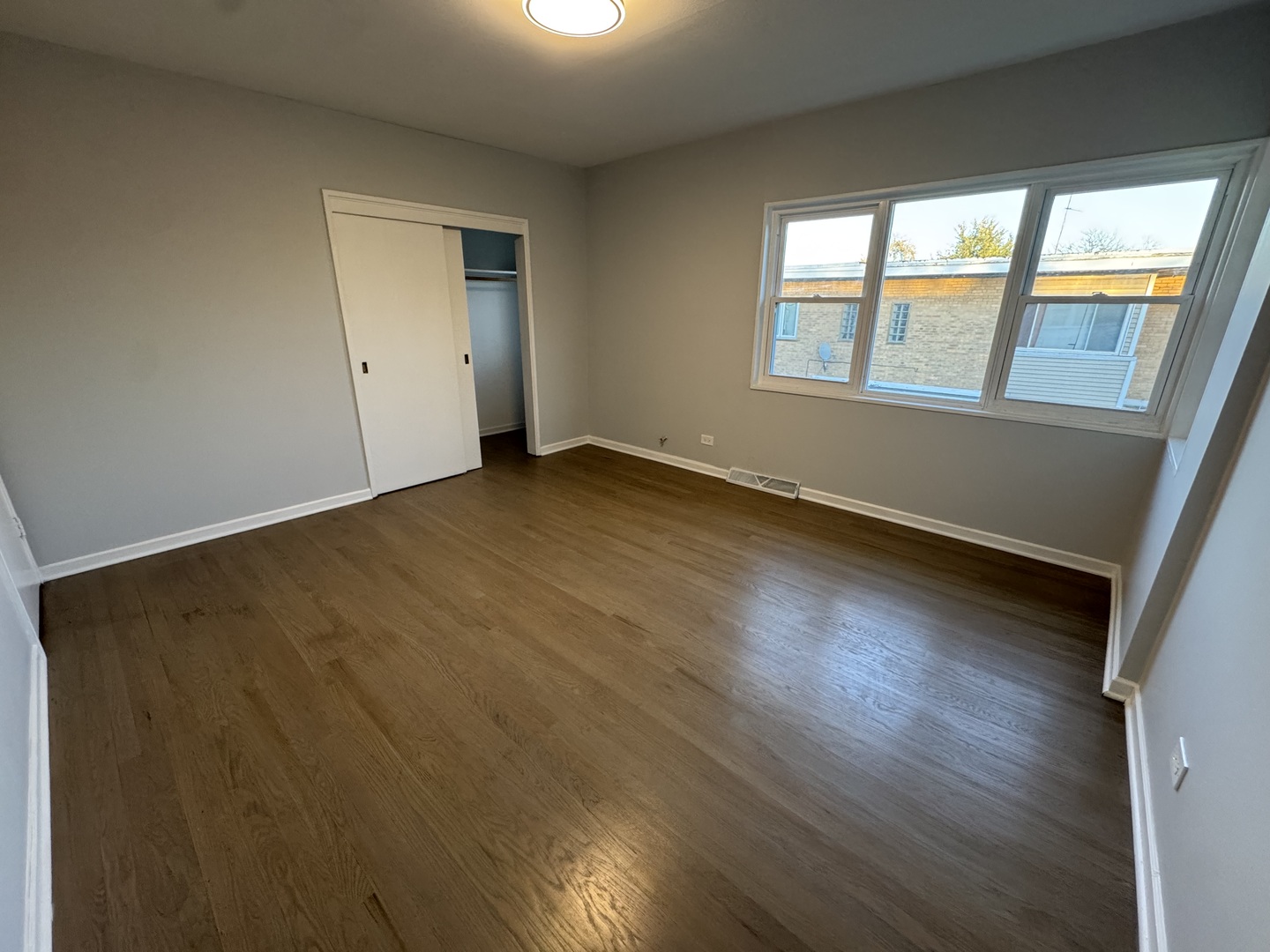 4912 Crain Street, Unit C Skokie, IL 60077 - Photo 12 of 15 a view of an empty room with wooden floor and windows