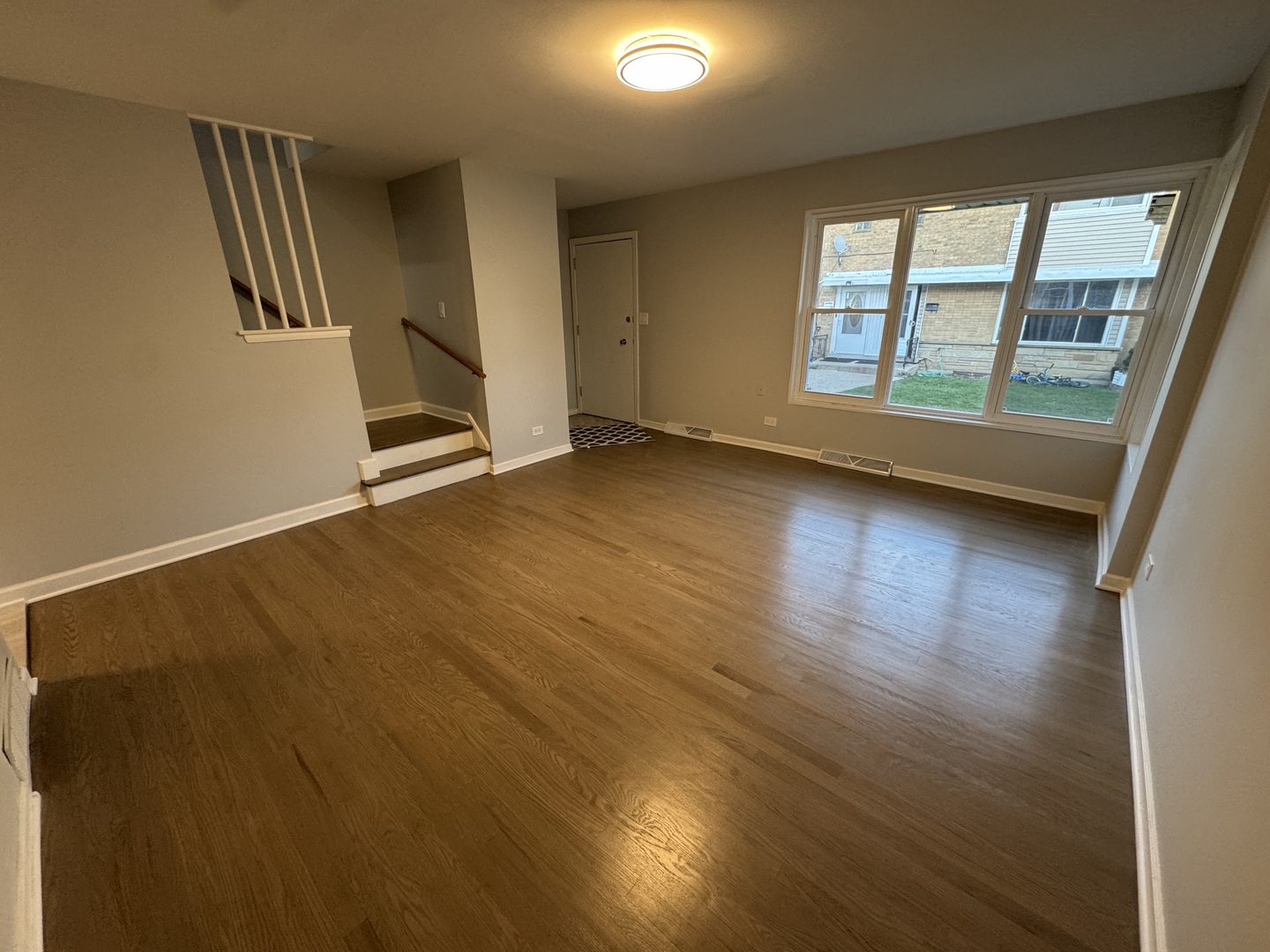 4912 Crain Street, Unit C Skokie, IL 60077 - Photo 4 of 15 an empty room with wooden floor and windows