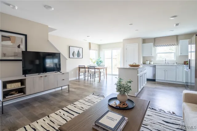 a living room with granite countertop furniture a flat screen tv and kitchen view