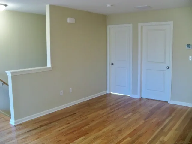 a view of an empty room with wooden floor and closet