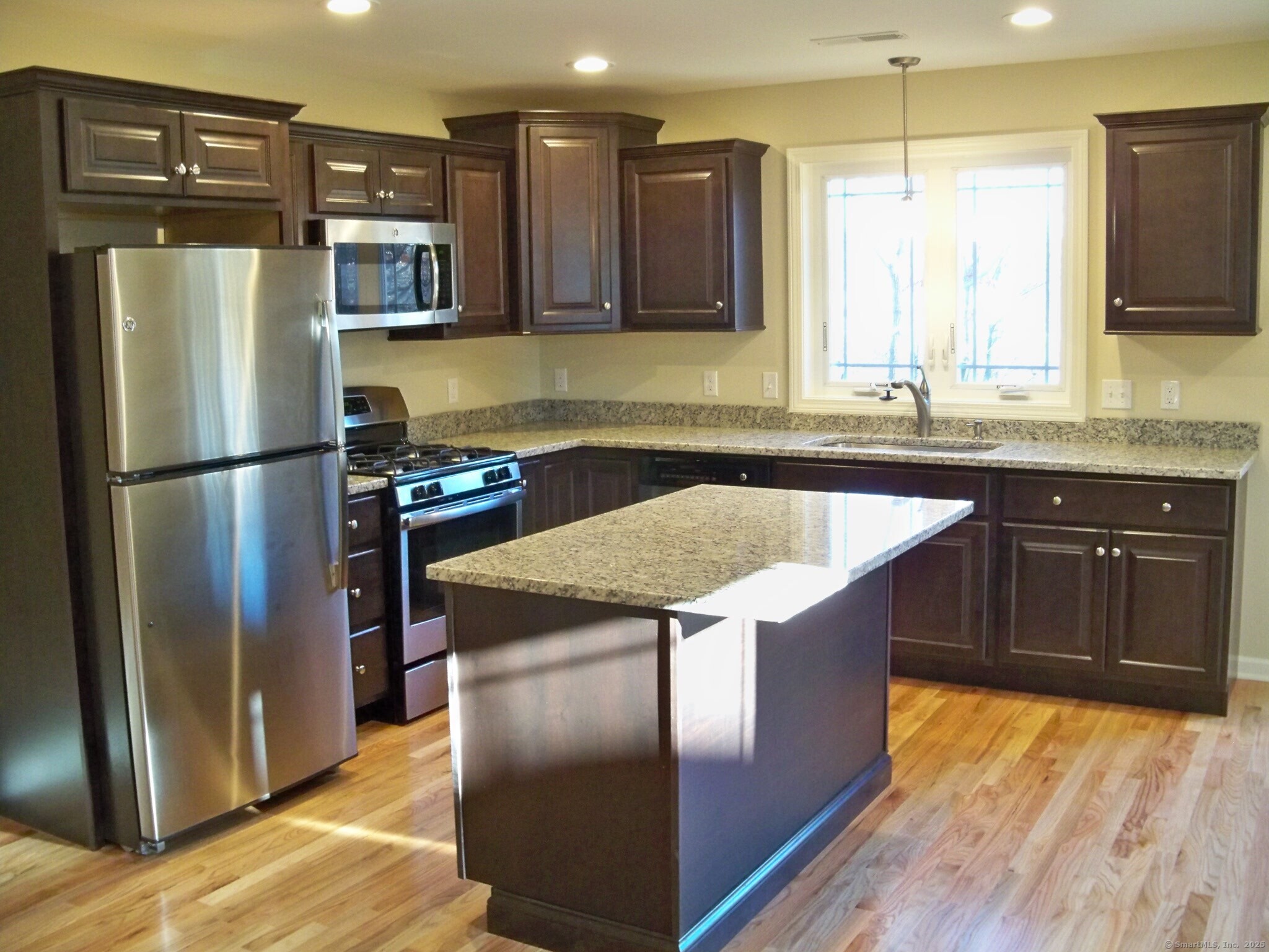 404 Main Street, Unit 13 Wallingford, CT 06492 - Photo 2 of 19 a kitchen with stainless steel appliances granite countertop a refrigerator a sink a stove a microwave and island