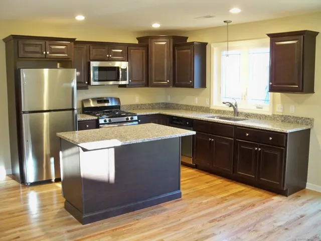 a kitchen with stainless steel appliances granite countertop a stove a refrigerator a sink a microwave and wooden cabinets