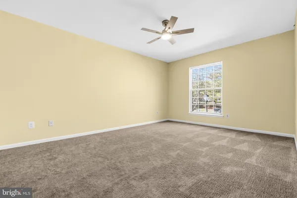 an empty room with closet and a ceiling fan