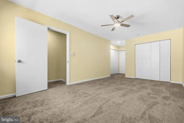 a view of a livingroom with a ceiling fan & windows