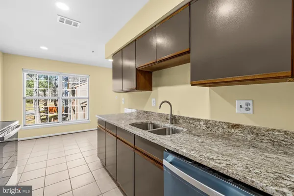 a kitchen with granite countertop a sink a stove and cabinets