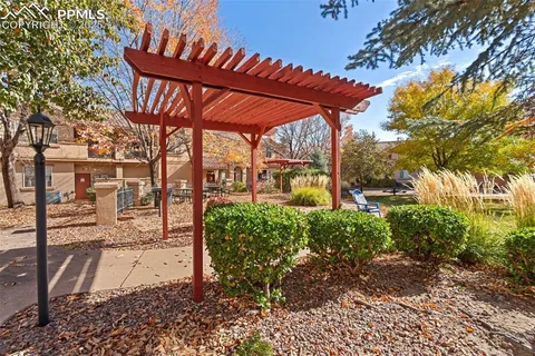 a view of a patio with table and chairs under an umbrella with a large tree