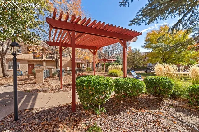 a view of a patio with table and chairs under an umbrella with a large tree