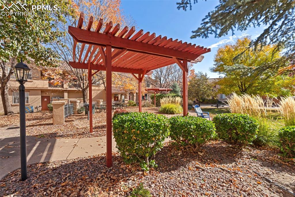 3231 Apogee View Colorado Springs, CO 80906 - Photo 37 of 38 a view of a patio with table and chairs under an umbrella with a large tree