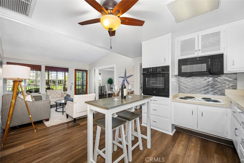 1621 Interlachen Road, Unit 265B Seal Beach, CA 90740 - Photo 27 of 36 a kitchen with stainless steel appliances granite countertop a stove top oven a sink a dining table and chairs with wooden floor