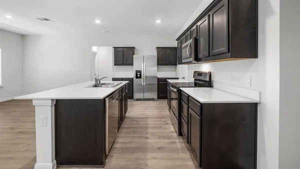a kitchen with stainless steel appliances a sink stove top oven and wooden cabinets