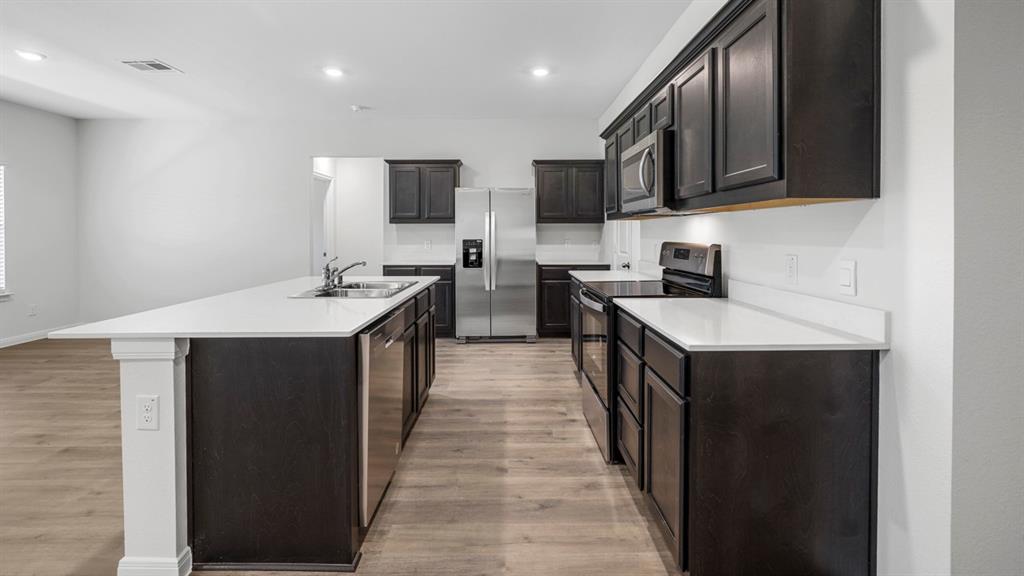 1921 Reveille Way Terrell, TX 75160 - Photo 12 of 25 a kitchen with stainless steel appliances a sink stove top oven and wooden cabinets