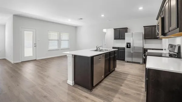a kitchen with stainless steel appliances granite countertop a sink a stove top oven a refrigerator with wooden floors