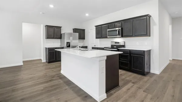 a kitchen with stainless steel appliances a stove top oven a sink dishwasher a refrigerator and cabinets with wooden floor