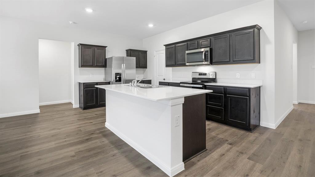 1921 Reveille Way Terrell, TX 75160 - Photo 14 of 25 a kitchen with stainless steel appliances a stove top oven a sink dishwasher a refrigerator and cabinets with wooden floor