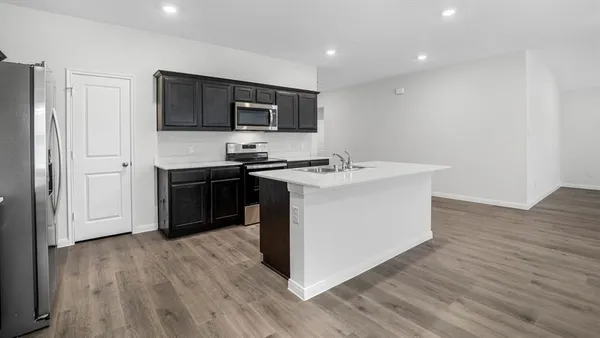 a kitchen with stainless steel appliances a sink a stove top oven a wooden floor