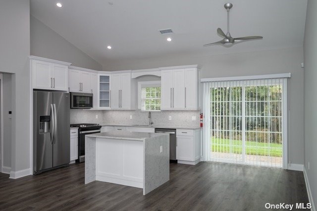 a kitchen with stainless steel appliances a stove top oven a refrigerator a sink and dishwasher with wooden floor