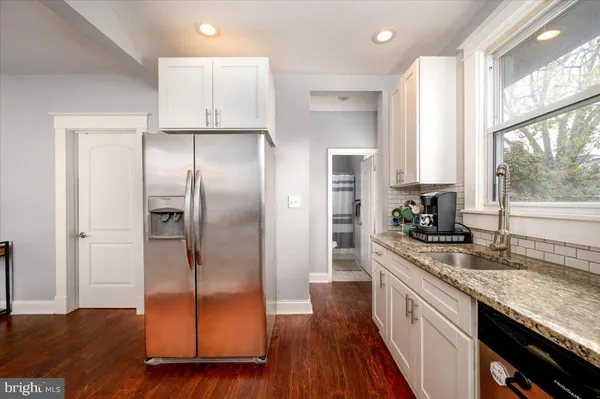 a kitchen with kitchen island granite countertop a sink appliances cabinets and wooden floor