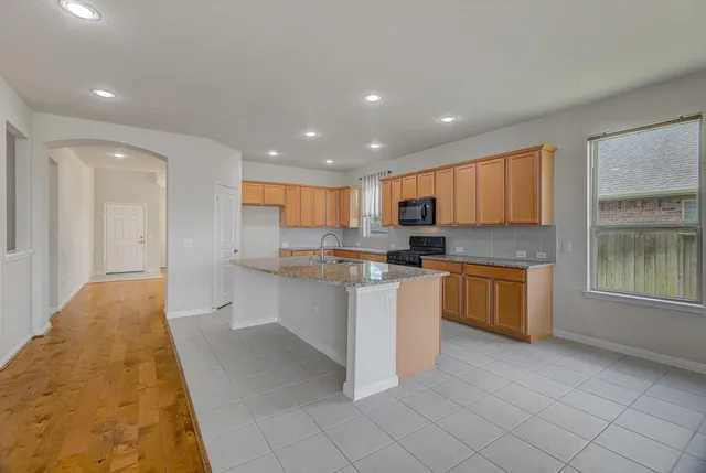 a view of kitchen with kitchen island stainless steel appliances sink cabinets and stove with wooden floor