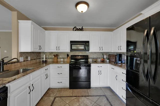a kitchen with granite countertop a refrigerator stove and sink