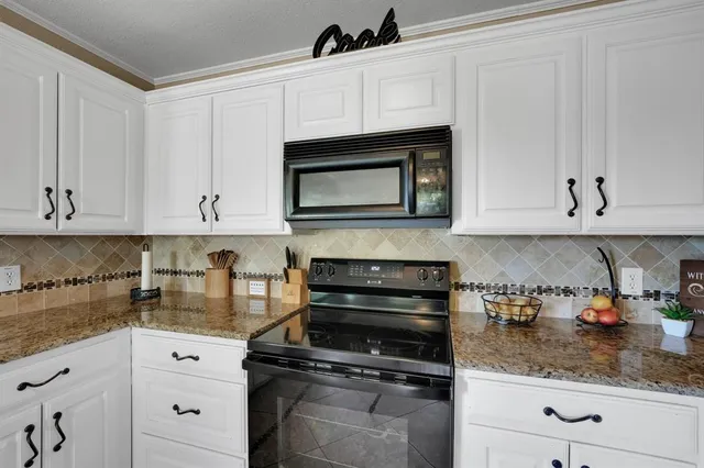a kitchen with stainless steel appliances granite countertop white cabinets and a stove a sink
