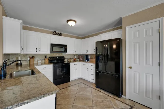 a kitchen with a refrigerator a microwave a sink and cabinets