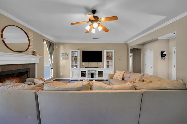 a living room with fireplace furniture a flat screen tv and a chandelier