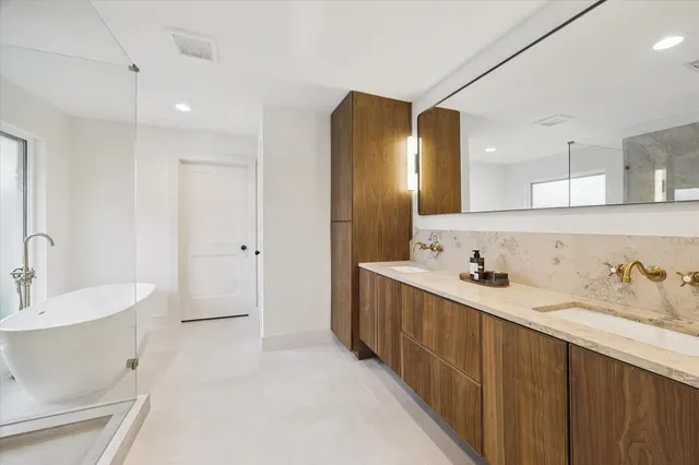 a bathroom with a double vanity sink mirror and bathtub