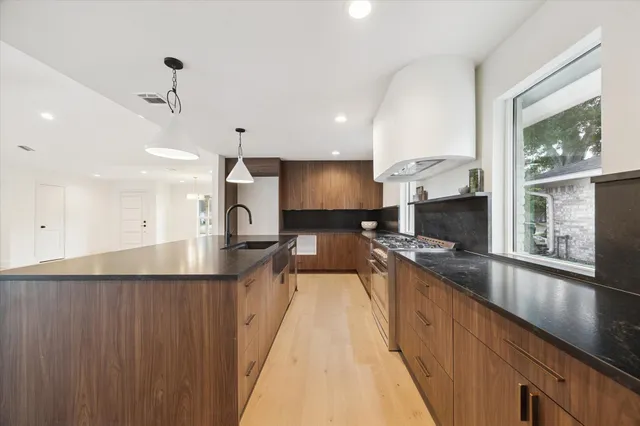 a large kitchen with stainless steel appliances a large counter top a stove a chimney a sink and a large window