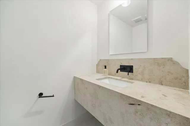 a bathroom with a granite countertop sink and white cabinets