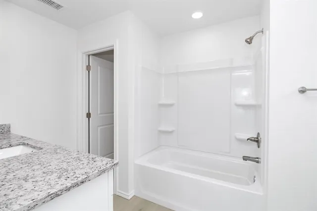 a bathroom with a granite countertop bathtub shower and vanity