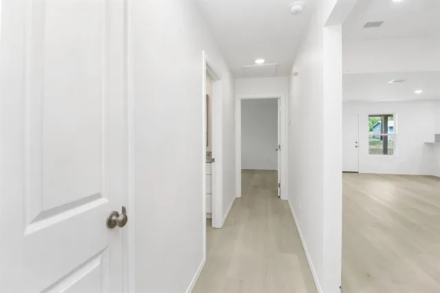 a view of a hallway with wooden floor and a bathroom
