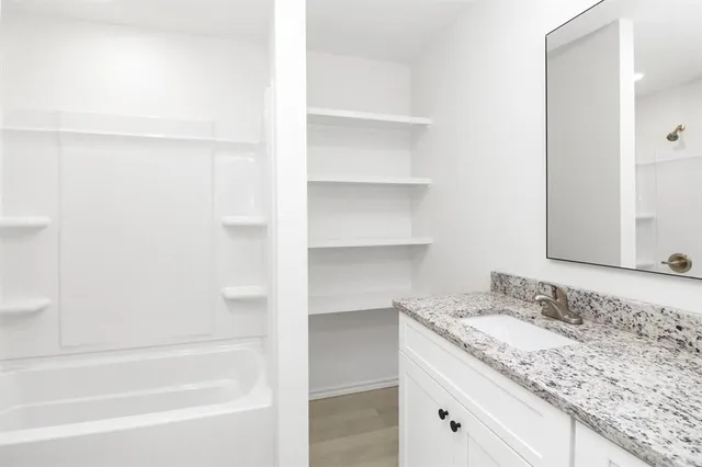a bathroom with a granite countertop sink and a bathtub