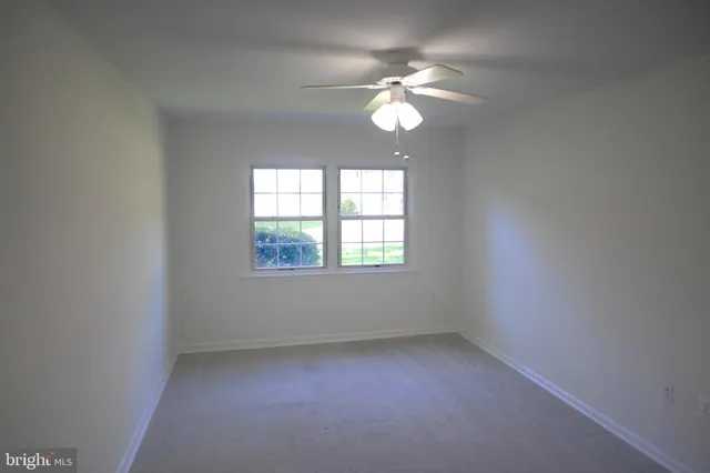 an empty room with a chandelier fan and windows