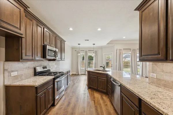a kitchen with stainless steel appliances granite countertop a stove a sink and a refrigerator